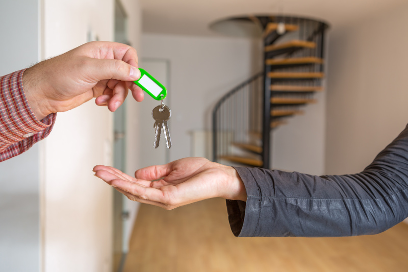 Der Wohnungsschlüssel wird übergeben, im Hintergrund ist eine leere Maisonette Wohnung zu sehen